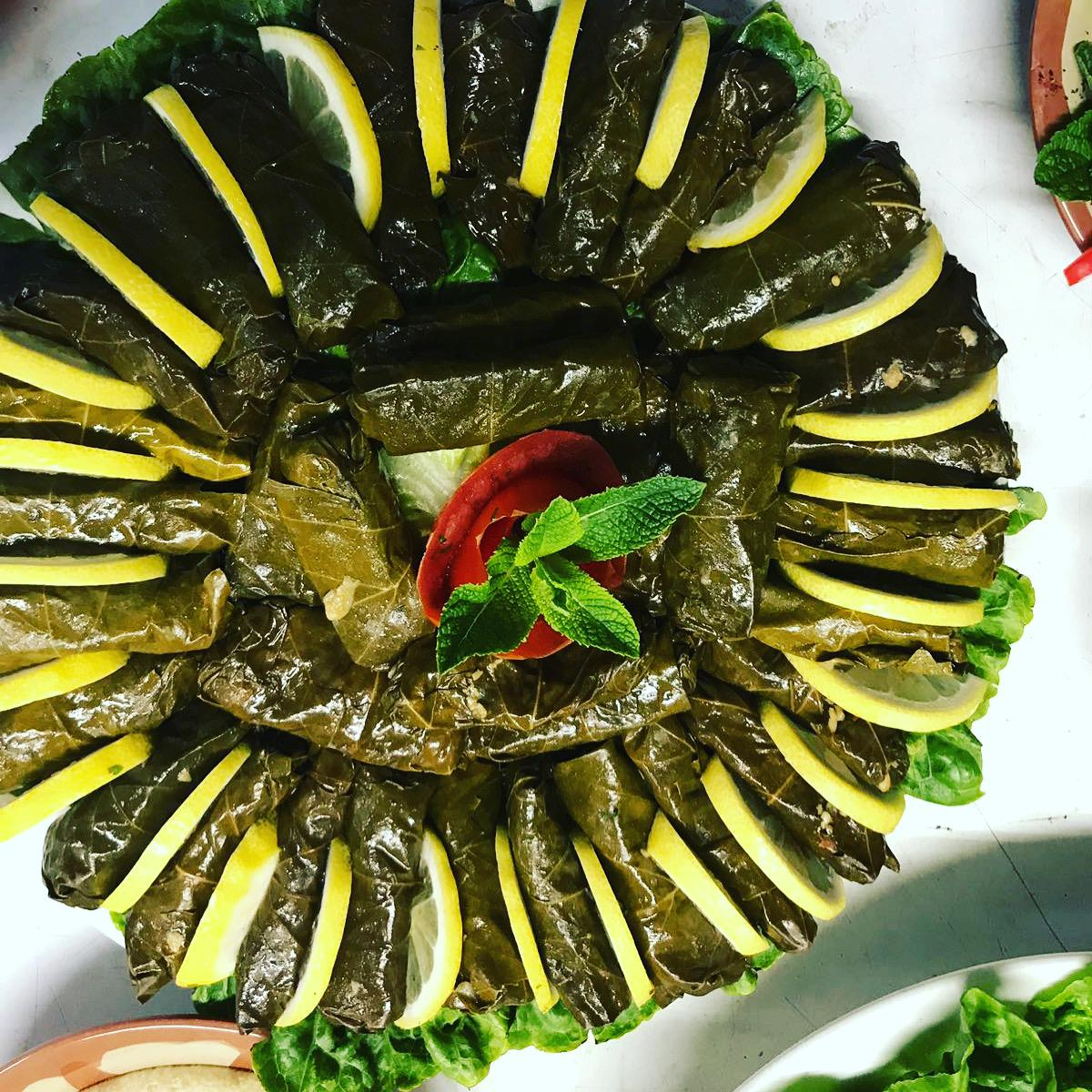Warak enab plated with lemon wedges